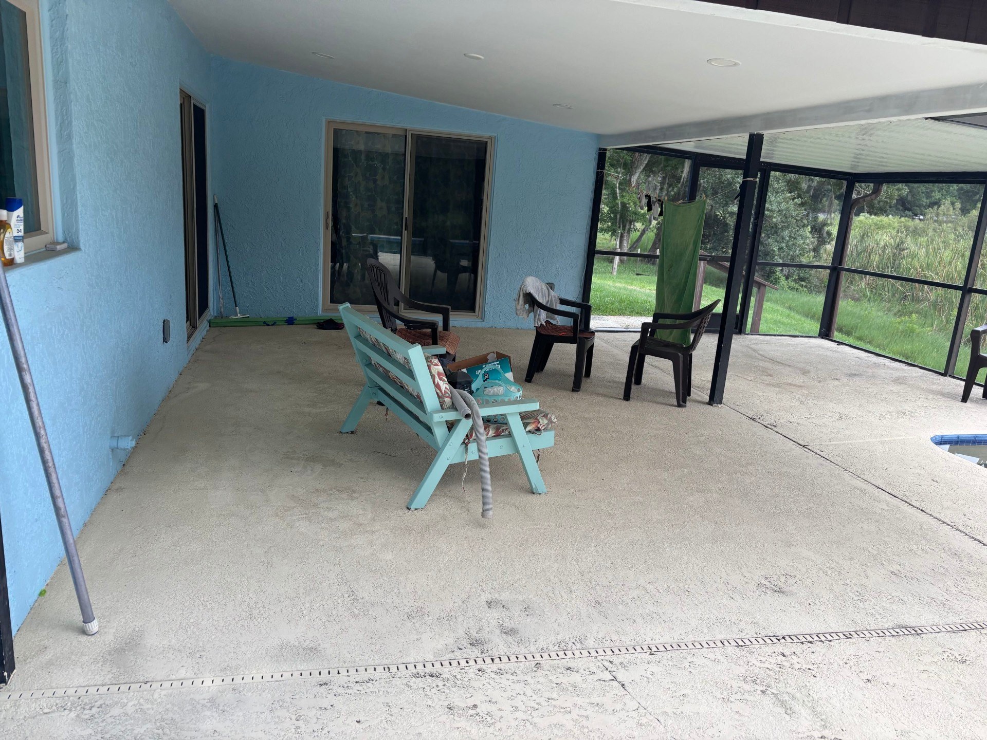 Dirty screened pool patio pressure washed back to clean concrete — before